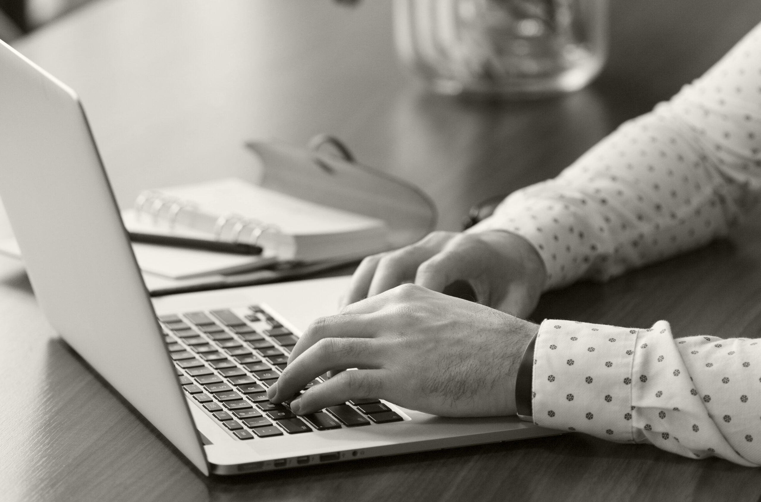 Handen van iemand die op een laptop typt