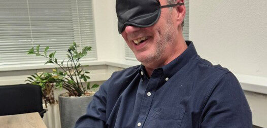 man met lapje voor ogen probeert zijn telefoon te bedienen